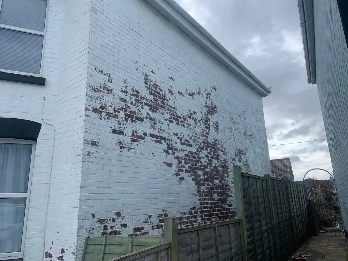Peeling paint on a brick wall before redecoration in Great Torrington